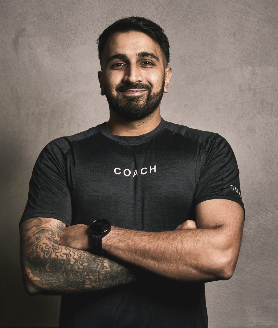 Saran Kalsi, arms crossed, wearing a black Equinox coach t-shirt